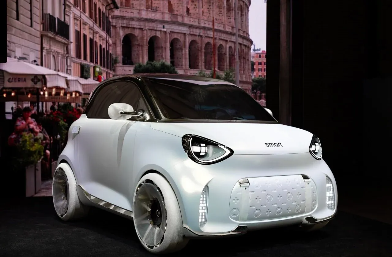 smart — przód i bok, biały concept car na stoisku targowym, w tle Koloseum