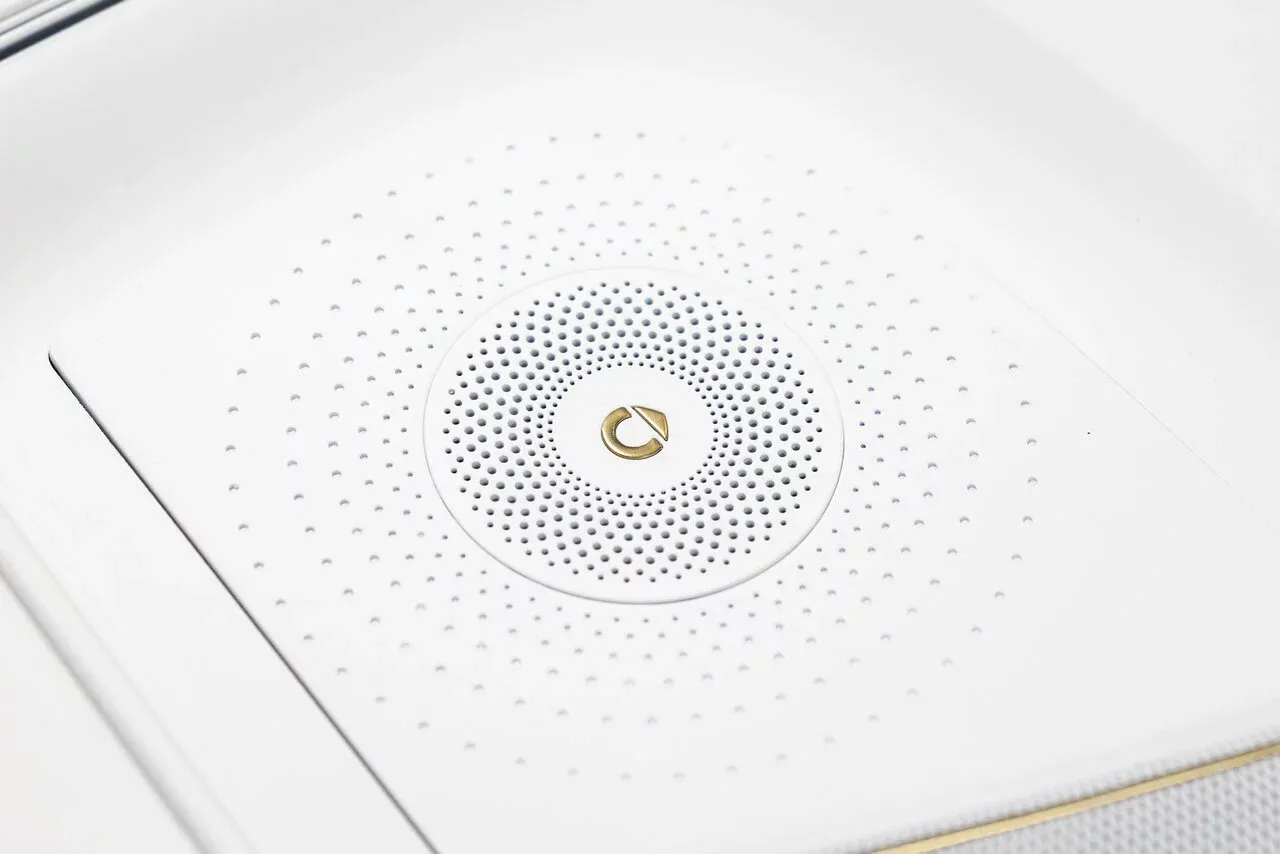 smart Concept #2 — detal wnętrza: panel głośnika z okrągłym złotym logotypem marki